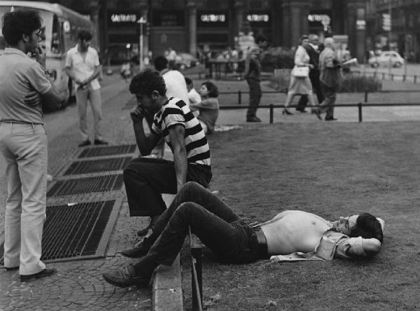 Mondo Beat. Milano - Piazza del Duomo - Ragazzi: ragazzo seduto su carriera dell'aiuola e ragazzo sdraiato nel prato - Riposo