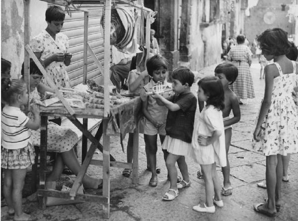 Napoli: Seconda scelta. Napoli - Strada - Bambine davanti a banchetto con giochi - Bambina con tromba - Gemelle