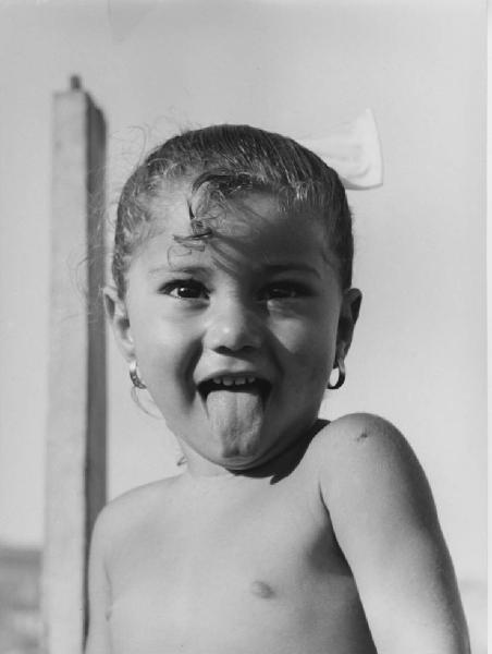 Napoli: Bimbi, volti. Napoli - Ritratto infantile - Bambina nuda - Lingua fuori - Orecchini, fiocco