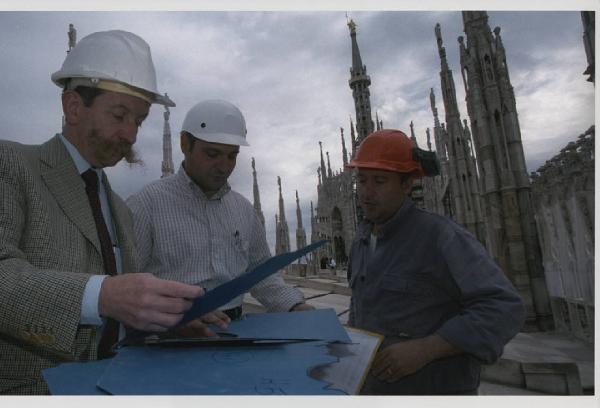 Economia e sviluppo. Milano - Duomo di Milano - Ritratto di gruppo - Uomini, operai e tecnici - Riunione di cantiere sulle guglie