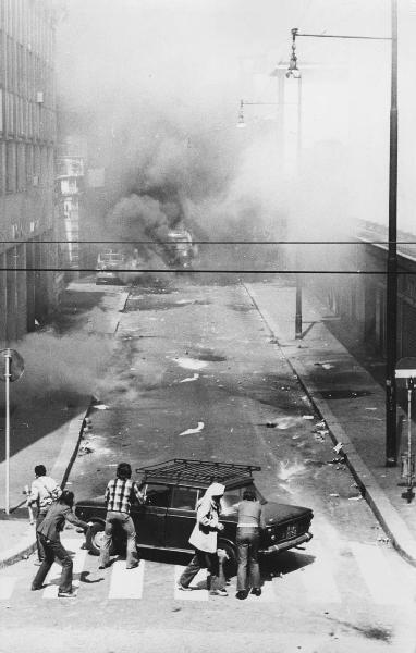 Zibecchi caso. Milano - Via Antonio Mancini - Scontro violento - Attacco alla sede del M.S.I - Gruppo di manifestanti - Barricata con automobile - Autocarri militari - Incendio, fumo