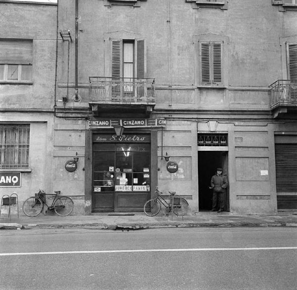 Milano - Via Ripamonti 342 - Osteria S. Pietro, esterno - Ritratto maschile: uomo dietro la porta a vetri - Uomo sulla soglia di un portone - Biciclette