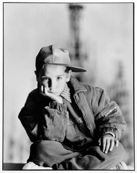 Campagna pubblicitaria per Trussardi Junior - Bambino con viso appoggiato alla mano: giacchetta di jeans e berretto da baseball