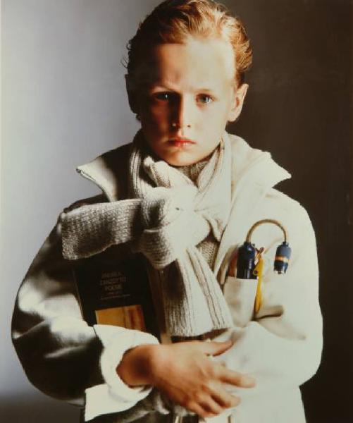 Campagna pubblicitaria per Trussardi Junior - Bambino con giacca di velluto bianca, maglione e sciarpa coordinati - Lampadina portatile nel taschino - Libro di Andrea Zanzotto