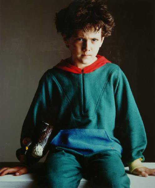 Campagna pubblicitaria per Trussardi Junior - Bambino seduto; tuta da ginnastica verde e cappuccio rosso