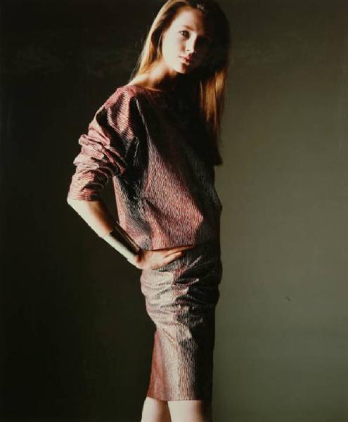 Campagna pubblicitaria per Trussardi Donna - Modella con mani sui fianchi: completo camicia e gonna marroni - Largo bracciale metallico