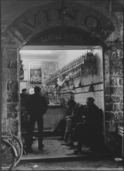 Firenze - Cantina ristoro: negozio di vini visto dalla strada - Piccole damigiane appese - Uomini seduti - Biciclette