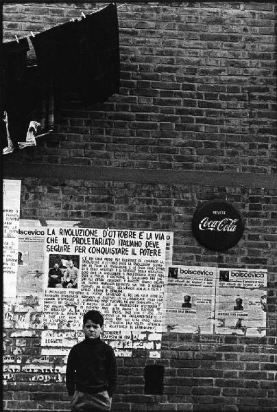 Firenze - Strada - Ritratto infantile: bambino davanti a manifesti inneggianti la Rivoluzione d'Ottobre - Pubblicità della Coca-Cola