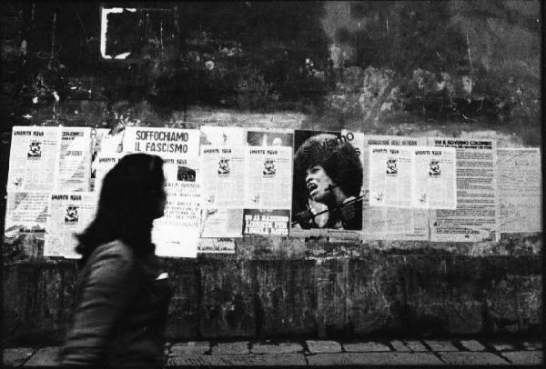 Firenze - Strada - Ritratto femminile: donna cammina davanti a manifesti di propaganda politica