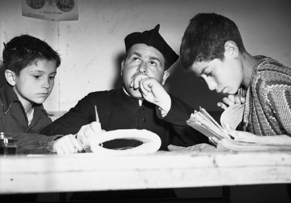 Italia del Sud. Puglia - Bari - Villaggio dei Fanciulli - bambini ai banchi di scuola - prete