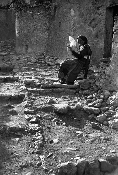 Italia del Sud. Calabria - donna carda la lana sulla soglia di casa