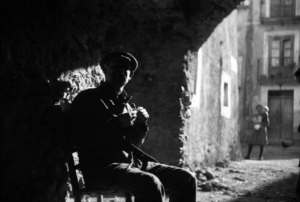 Italia del Sud. Calabria - uomo siede all'ombra di un passaggio porticato