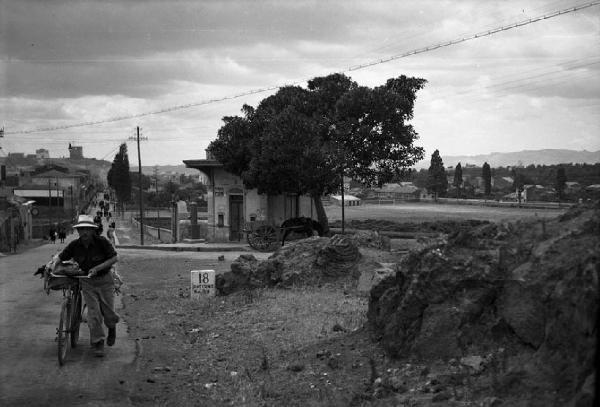 Italia del Sud. Sicilia - strada - pietra miliare con indicazione di Paternò - uomo in bicicletta