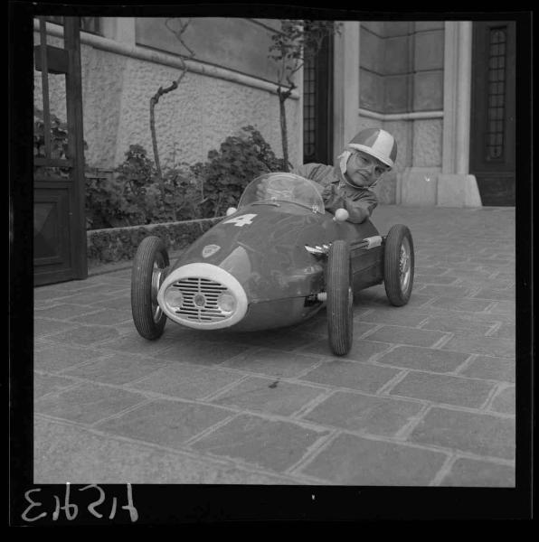 Ritratto infantile - Famiglia Assunto - Bambino al volante di un'automobile giocattolo - Abitazione - Cortile