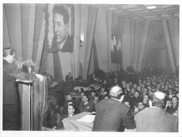 Camera del Lavoro - Salone "Di Vittorio" - Interno - VII Congresso provinciale dei metalmeccanici - Giuseppe Sacchi al microfono - Platea - Sulla parete immagine di Giuseppe Di Vittorio e bandiere italiane