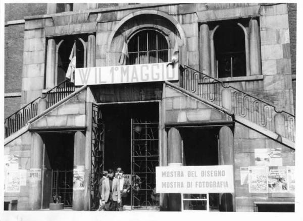 Ingresso della Camera del Lavoro - Sulla facciata striscione "W IL 1° MAGGIO" - Cartello "Mostra del disegno, mostra di fotografia"