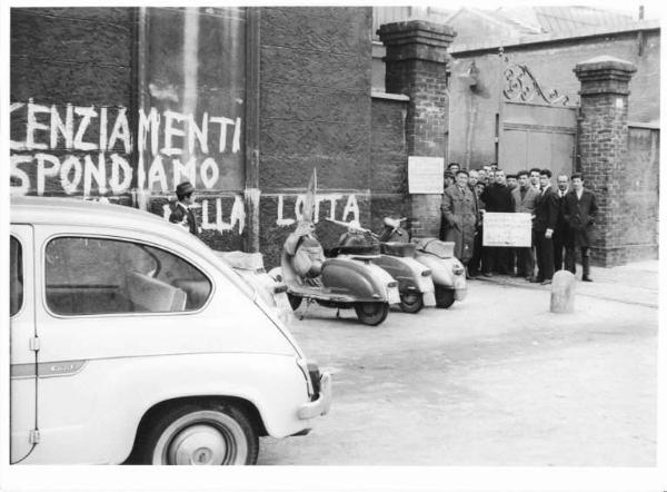 Sciopero dei lavoratori delle Acciaierie Elettriche di Sesto San Giovanni contro la richiesta di 65 licenziamenti - Operai davanti all'ingresso della fabbrica - Scritte sul muro - Motociclette