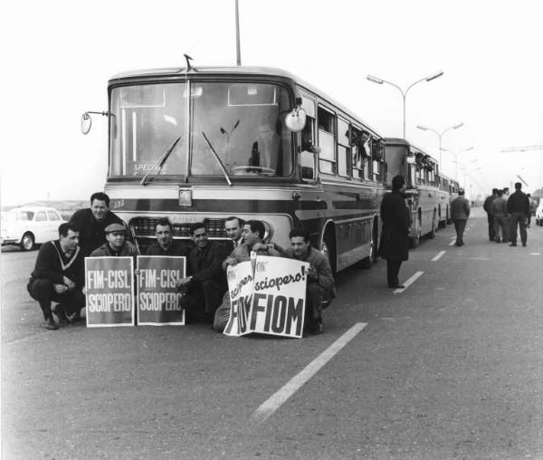 Sciopero dei lavoratori dell'Alfa Romeo di Arese - Ritratto di gruppo - Lavoratori davanti al pullman speciale che li porta alla manifestazione - Cartelli Fiom e Fim Cisl