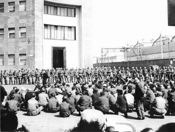 Sciopero dei lavoratori della Innocenti - Presidio - Operai con tuta da lavoro seduti per terra davanti alla fabbrica