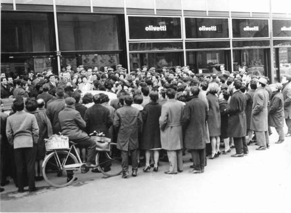 Sciopero dei lavoratori della Olivetti contro i licenziamenti - Comizio davanti alla sede milanese della Olivetti - Oratore e lavoratori - Marchio della Olivetti