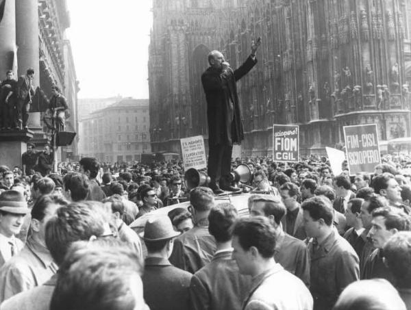 Sciopero dei lavoratori metalmeccanici per il contratto - Piazza del Duomo - Comizio - Guido Venegoni al microfono sul tetto di un'auto - Cartelli di sciopero Fiom Cgil e Fim Cisl