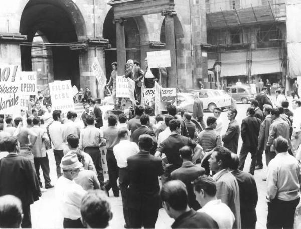 Sciopero dei lavoratori edili per il nuovo contratto - Comizio in piazza Mercanti - Oratore al microfono - Cartelli di sciopero Cgil, Cisl, Uil