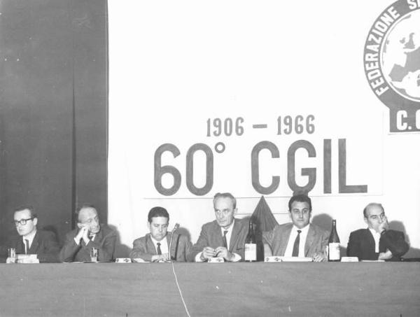 Camera del Lavoro - Salone "Di Vittorio" - Interno - 60° anniversario della Cgil - Tavolo della presidenza, tra i relatori Lauro Casadio, Guido Venegoni, Aldo Bonaccini - Parola d'ordine - Stemma della Cgil