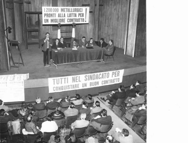 Piccolo Teatro - Interno - Assemblea dei lavoratori metalmeccanici per il rinnovo del contratto - Palco - Annio Breschi al microfono - Tavolo della presidenza - Tra gli oratori Pierluigi Perrotta e Pierre Carniti - Striscione - Ordine del giorno