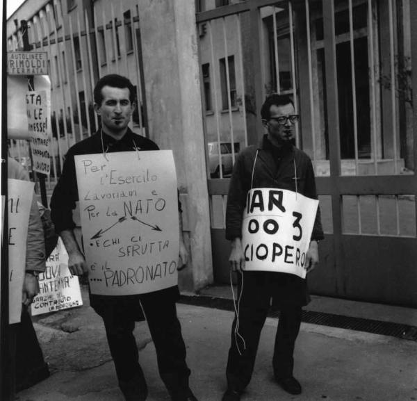 Sciopero dei lavoratori della Fiar - Stabilimento 003 - Ingresso della fabbrica - Presidio - Lavoratori con cartelli di protesta - Operaio con grembiule da lavoro