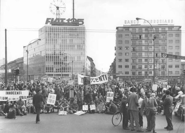 Sciopero dei lavoratori della Innocenti - Corteo fermo in piazzale Loreto - Sindacalisti: Leonardo Banfi, Annio Breschi, Pierre Carniti - Operai con tuta da lavoro - Striscione - Cartelli di sciopero Fiom Cgil, Fim Cisl, Uilm