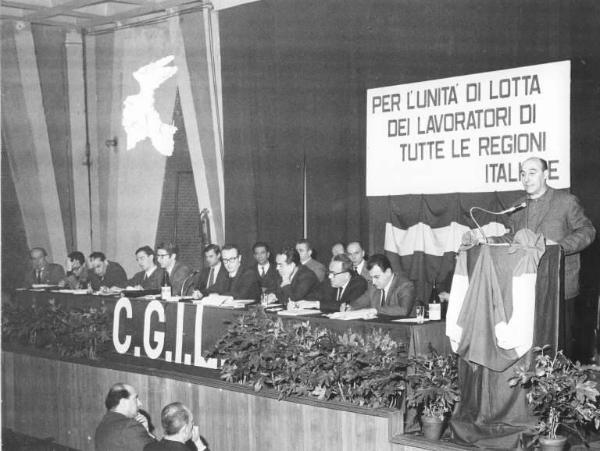 Camera del Lavoro - Salone "Di Vittorio" - Interno - 1° Congresso regionale Lombardo della Cgil - Palco - Tavolo della presidenza - Aldo Bonaccini al microfono - Parola d'ordine del congresso - Bandiera