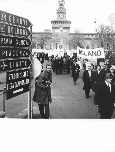 Sciopero nazionale unitario dei lavoratori tessili - Corteo davanti al Castello Sforzesco di Milano - Cartelli di protesta - Forze dell'ordine - Cineoperatore - Cartelli stradali