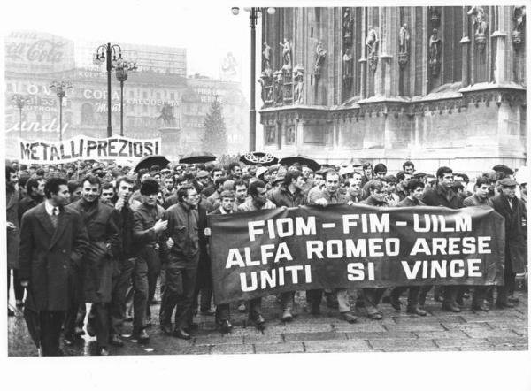 Manifestazione silenziosa dei lavoratori metalmeccanici per il contratto di lavoro e contro l'arresto di 4 lavoratori - Corteo sotto la pioggia in piazza del Duomo - Spezzone lavoratori Alfa Romeo - Striscione - Pubblicità sui palazzi