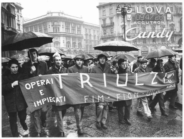 Manifestazione silenziosa dei lavoratori metalmeccanici per il contratto di lavoro e contro l'arresto di 4 lavoratori - Corteo sotto la pioggia in piazza del Duomo - Spezzone lavoratori della Triulzi - Striscione - Pubblicità sui palazzi