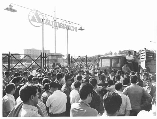 Sciopero dei lavoratori della Autobianchi contro le sospensioni - Comizio davanti all'ingresso della fabbrica - Lavoratori - Auto con altoparlante - Camion - Insegna Autobianchi