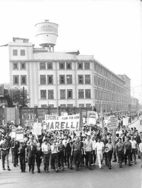 Sciopero dei lavoratori della Ercole Marelli - Corteo sfila davanti alla Magneti Marelli - Operai con tuta da lavoro - Striscione - Cartelli Fim, Fiom, Uilm - Insegna Magneti Marelli