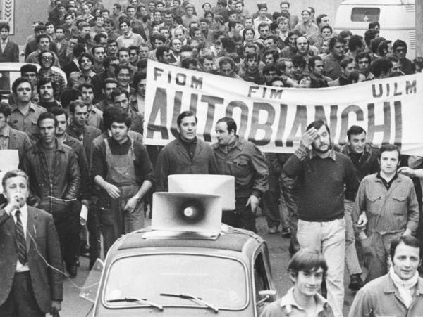 Sciopero dei lavoratori della Autobianchi per il superamento dei cottimi e delle qualifiche - Corteo - Operai con tuta da lavoro - Striscione - Auto con altoparlante