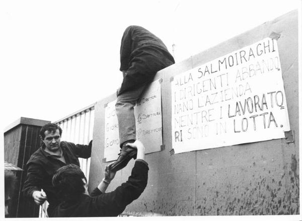 Sciopero dei lavoratori della Salmoiraghi - Operaio scavalca il muro della fabbrica - Cartelli di protesta sui muri della fabbrica