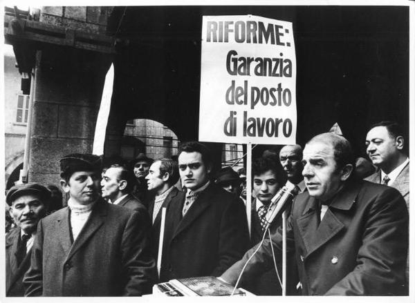 Sciopero dei lavoratori edili - Comizio in piazza Mercanti - Oratore al microfono - Cartello di rivendicazioni