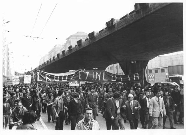 Sciopero dei lavoratori metalmeccanici della Zona Sempione in appoggio con la lotta della Crouzet - Corteo verso la Fiera sotto la sopraelevata - Operai con tuta da lavoro - Striscioni - Cartelli