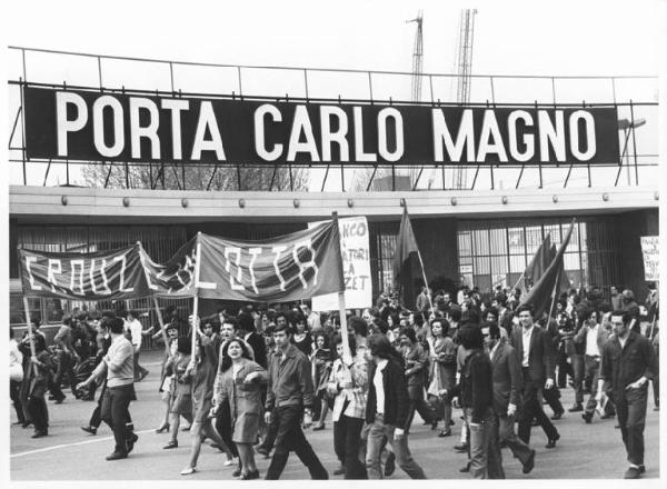 Sciopero dei lavoratori metalmeccanici della Zona Sempione in appoggio con la lotta della Crouzet - Corteo davanti alla Fiera - Operai con abito da lavoro - Striscioni - Cartelli - Bandiere - Insegna Porta Carlo Magno