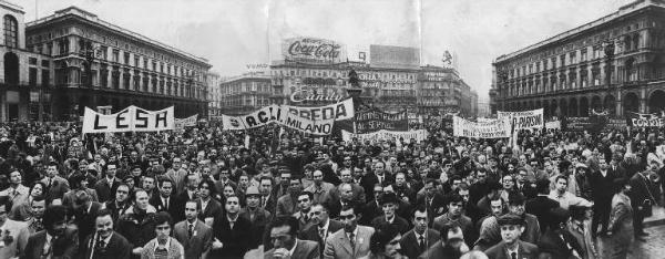 Manifestazione del primo maggio - Piazza del Duomo - Comizio - Folla di lavoratori - Striscioni - Monumento a Vittorio Emanuele II - Pubblicità sulle pareti dei palazzi