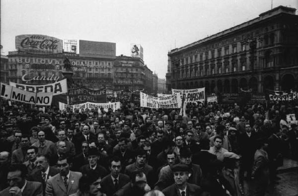 Manifestazione del primo maggio - Piazza del Duomo - Comizio - Folla di lavoratori - Striscioni - Monumento a Vittorio Emanuele II - Pubblicità sulle pareti dei palazzi