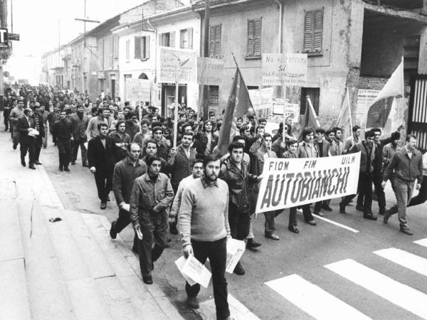 Sciopero dei lavoratori della Autobianchi per il superamento dei cottimi e delle qualifiche - Corteo - Operai con tuta da lavoro - Striscione - Cartelli di protesta - Bandiere Fim, Fiom, Uilm