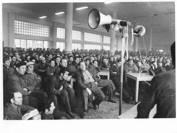 Om - Interno - Assemblea dei lavoratori - Operai con tuta da lavoro - Altoparlante