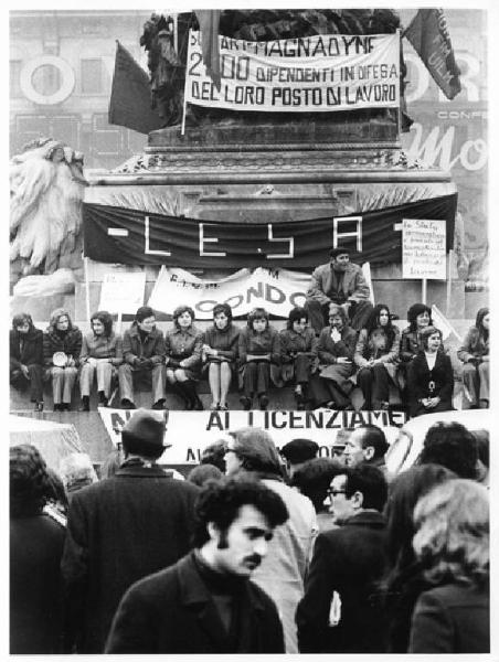 Sciopero dei lavoratori della Lesa - Presidio in piazza del Duomo - Lavoratrici sedute sul monumento a Vittorio Emanuele II - Striscioni - Bandiere Fiom, Fim, Uilm - Cartelli