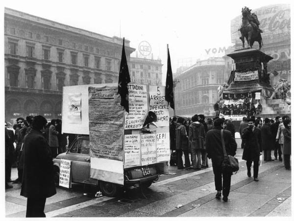 Sciopero dei lavoratori della Lesa - Presidio in piazza del Duomo - Auto con cartelli - Lavoratrici sedute sul monumento a Vittorio Emanuele II - Striscioni - Bandiere - Cartelli - Pubblicità sui palazzi