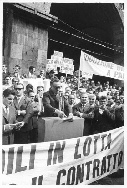 Sciopero regionale dei lavoratori edili - Piazza Mercanti - Comizio - Oratore al microfono - Cartelli sindacali di sciopero - Striscione