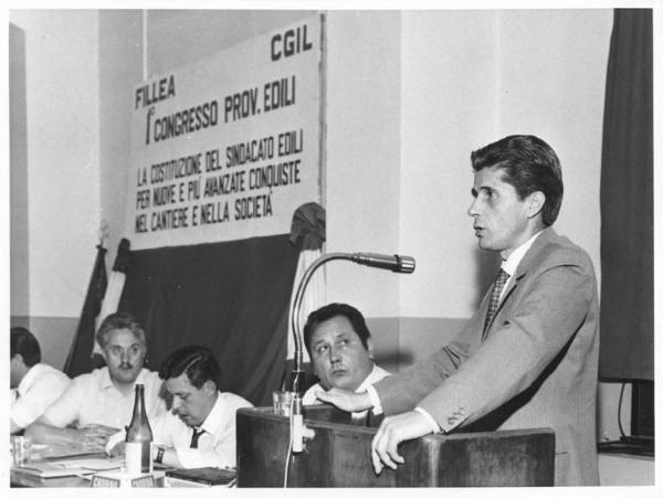 Camera del Lavoro - Sala "Bruno Buozzi" - Interno - Congresso provinciale edili - Tavolo della presidenza con, tra i sindacalisti, Lauro Casadio - Oratore al microfono - Parola d'ordine del congresso