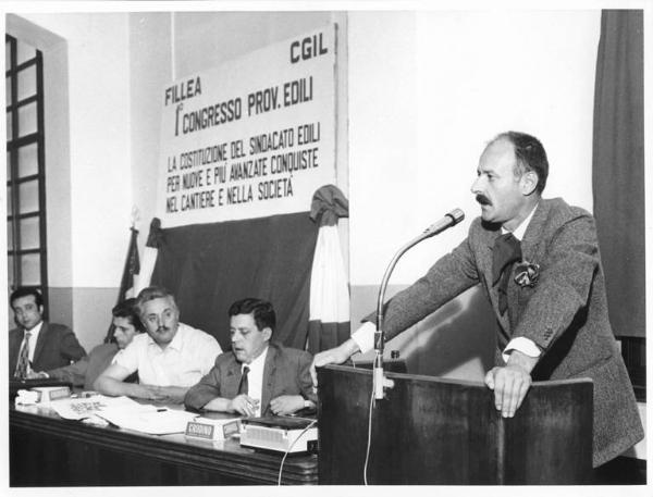 Camera del Lavoro - Sala "Bruno Buozzi" - Interno - Congresso provinciale edili - Tavolo della presidenza con, tra i sindacalisti, Lauro Casadio - Oratore al microfono - Parola d'ordine del congresso